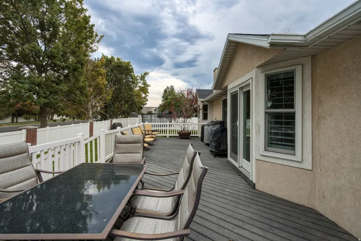 Expansive composite deck featuring composite decking with integrated dining and lounge areas, complemented by a white vinyl railing system