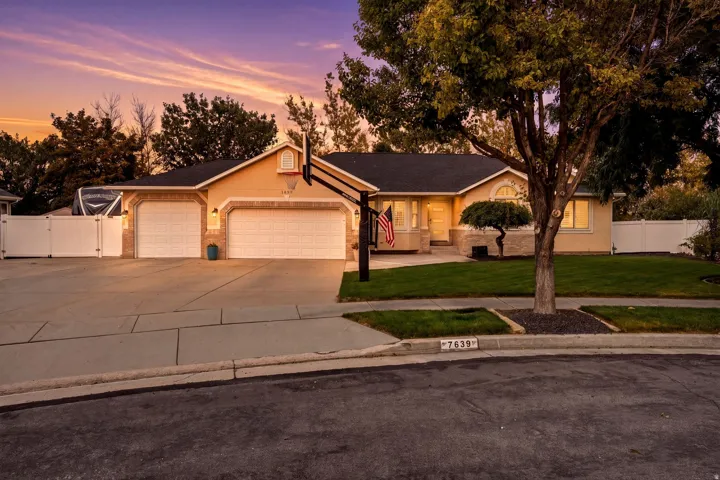 Elegant single-story residence featuring a stucco exterior, dual three-car garage with paneled doors, and a welcoming front entry with peaked roofline