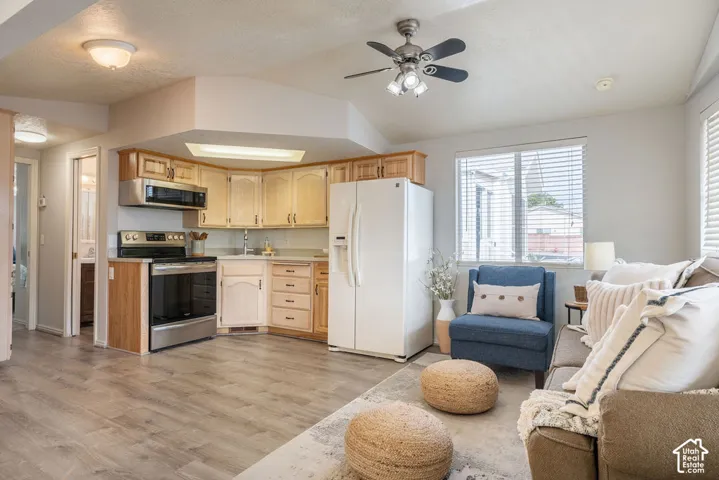 Kitchen featuring wood-finish cabinetry, stainless steel range with overhead microwave, and wood-finish flooring, complemented by a ceiling fan with integrated lighting
