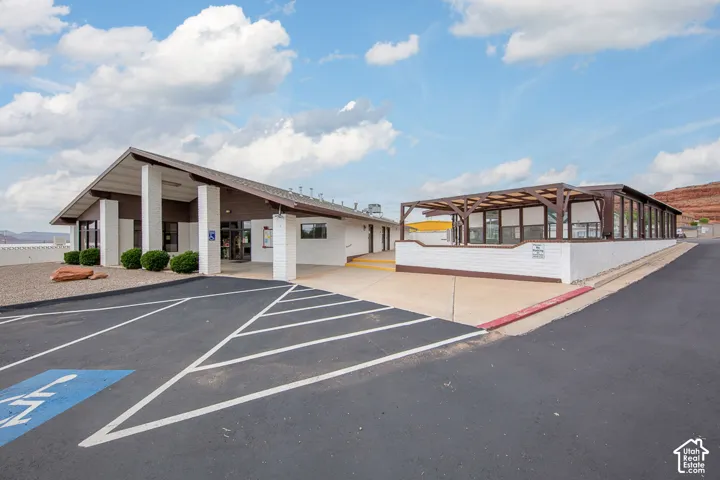 Asphalt parking area with painted lines, concrete walkways, and a covered outdoor structure with a pergola