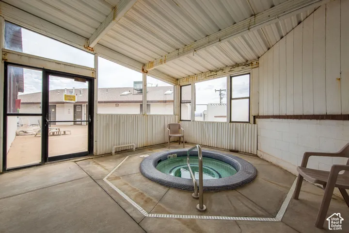 Indoor spa with tiled surround, concrete flooring, and an overhead metal roof