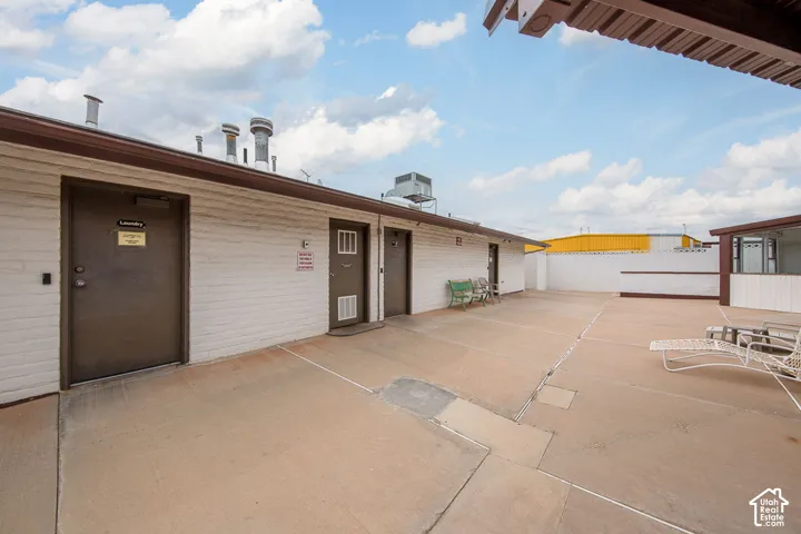 Expansive concrete patio area with white brick walls and a brown trim roofline