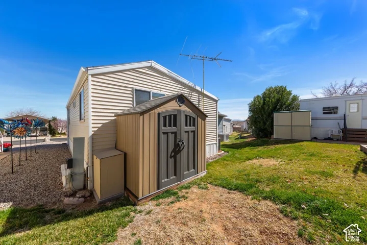 Exterior featuring horizontal siding, a detached storage shed, a gravel bed, and a grassy area