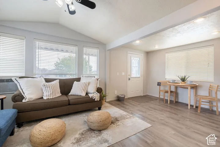 Vaulted ceilings, wood-finish flooring, recessed lighting, and multiple windows with horizontal blinds