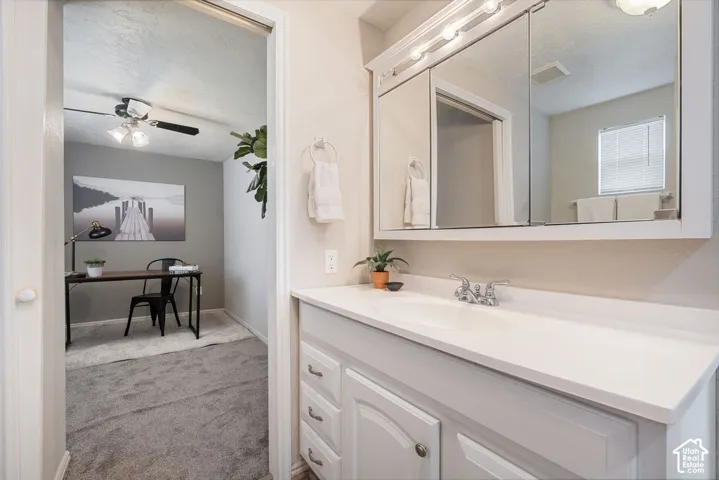 Vanity featuring a white countertop with an integrated sink, white cabinetry with multi-drawer storage, and a tri-paneled mirrored medicine cabinet