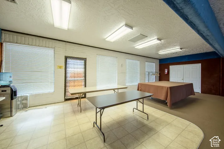 Spacious room featuring multiple windows with blinds, a tiled floor area, and recessed ceiling lighting
