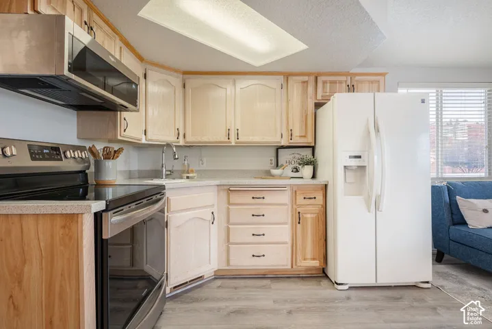 Kitchen featuring light wood cabinetry, stone-finish countertops, stainless steel appliances, and integrated recessed lighting
