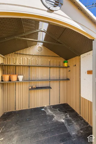 Interior storage shed featuring corrugated wall panels, built-in shelving, a pegboard storage system, and a skylight