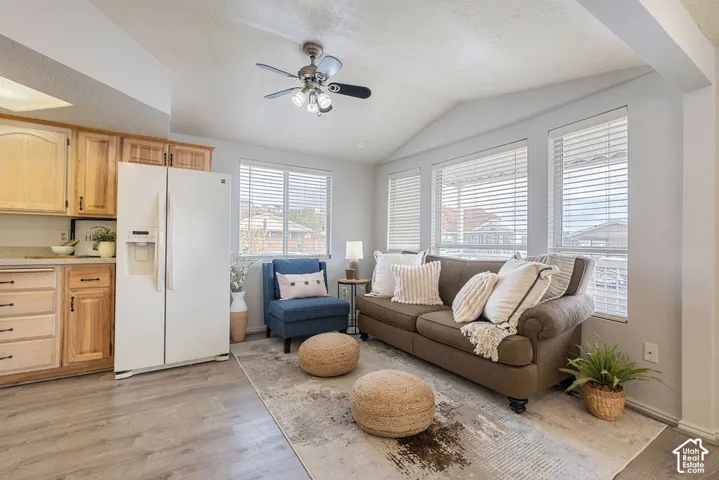 Vaulted ceilings, wood-finish flooring, natural wood cabinetry, and multiple windows with installed blinds