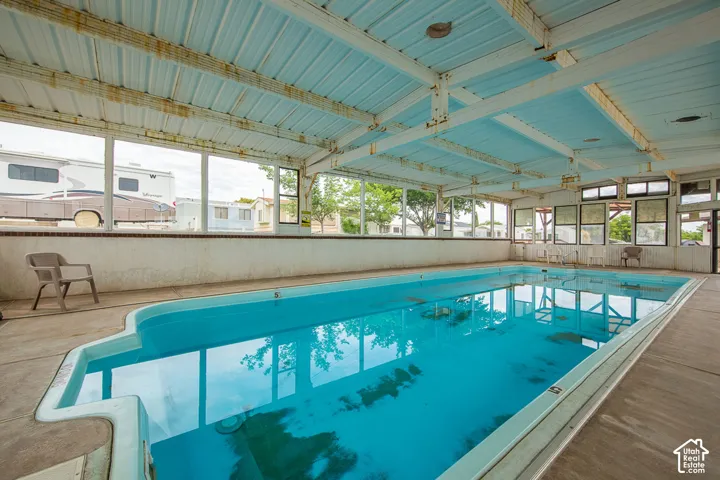 Indoor swimming pool with concrete decking, large windows, and a metal-framed ceiling