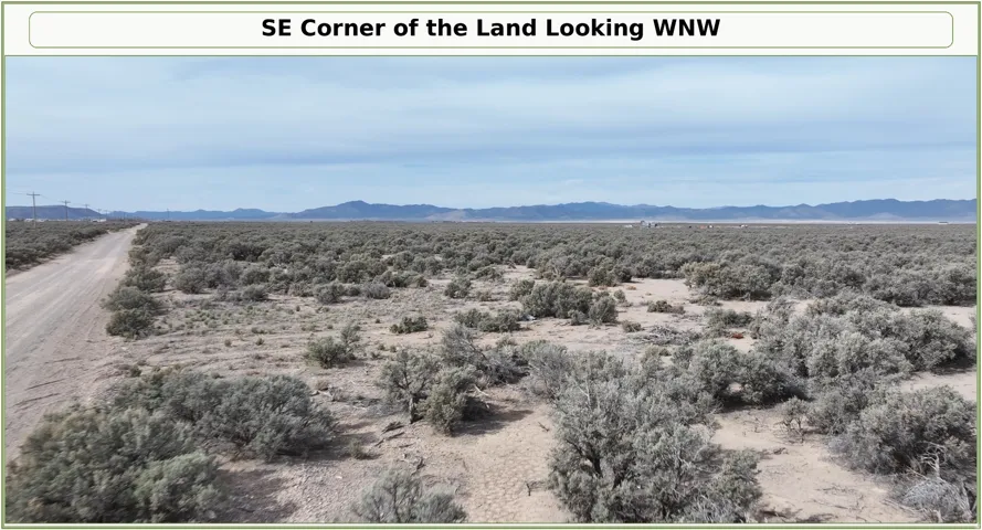Expansive vacant land featuring a dirt road and distant mountain ranges