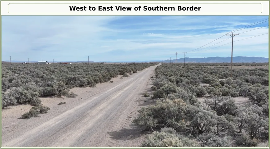 Expansive desert landscape featuring a dirt road, scattered brush, and visible utility poles