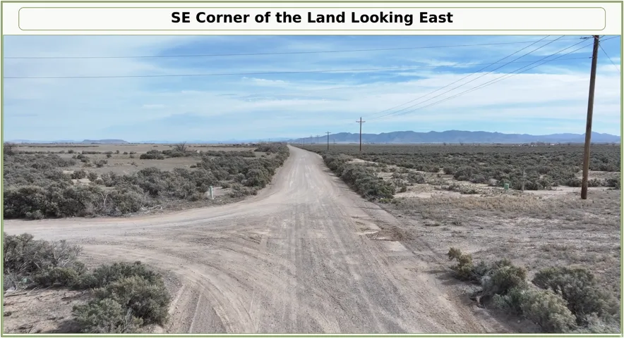 Expansive land parcel featuring a gravel road, natural desert foliage, and distant mountains under a blue sky