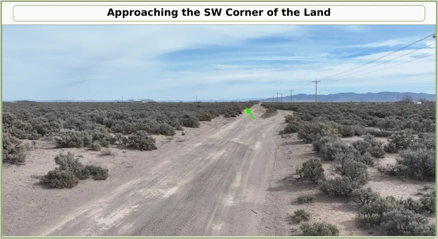 Expansive land parcel with natural vegetation, featuring a dirt road, utility poles, and distant mountains