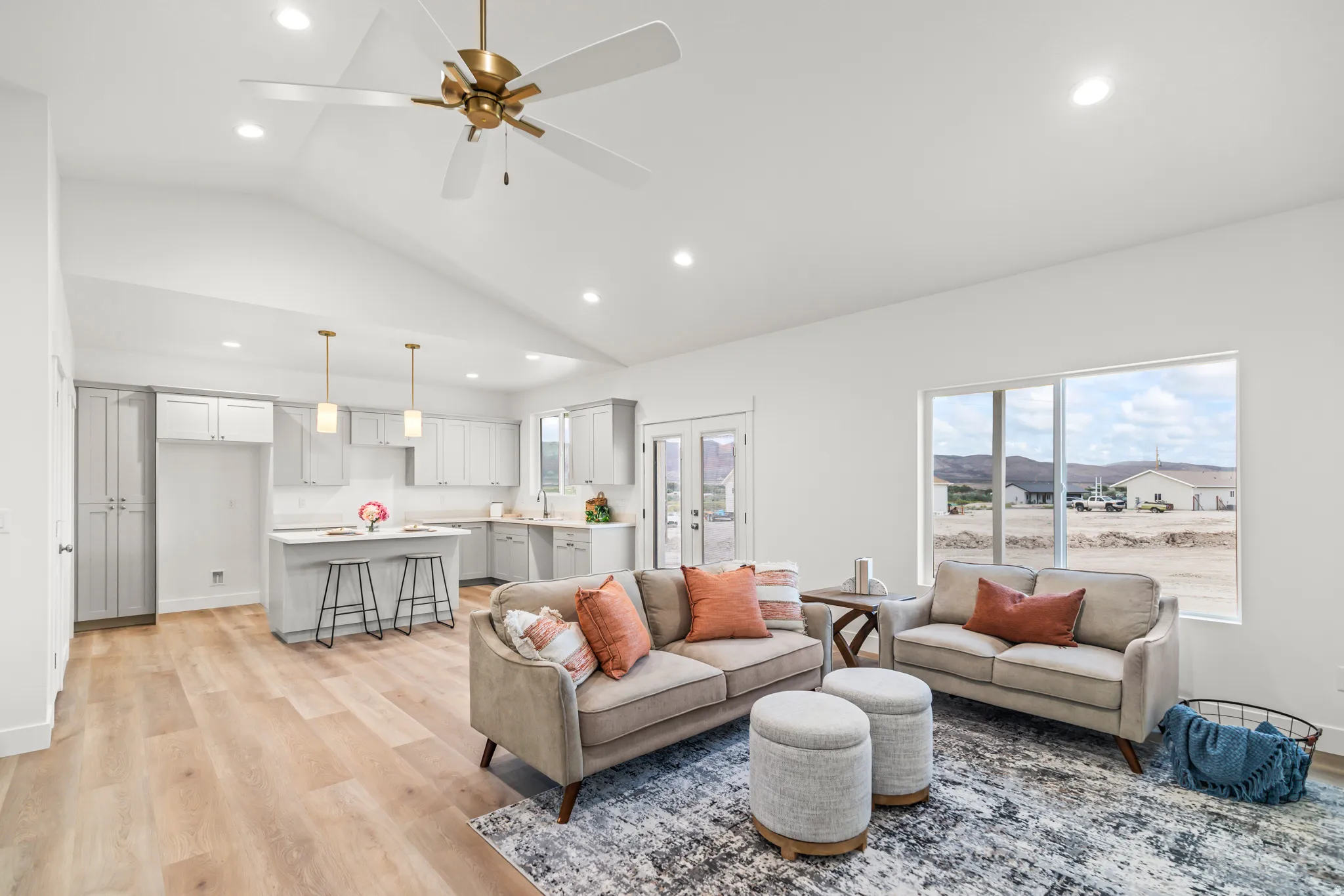 Vaulted ceilings with recessed lighting, wood-finish flooring, a kitchen island with pendant lighting, gray cabinetry, and expansive windows