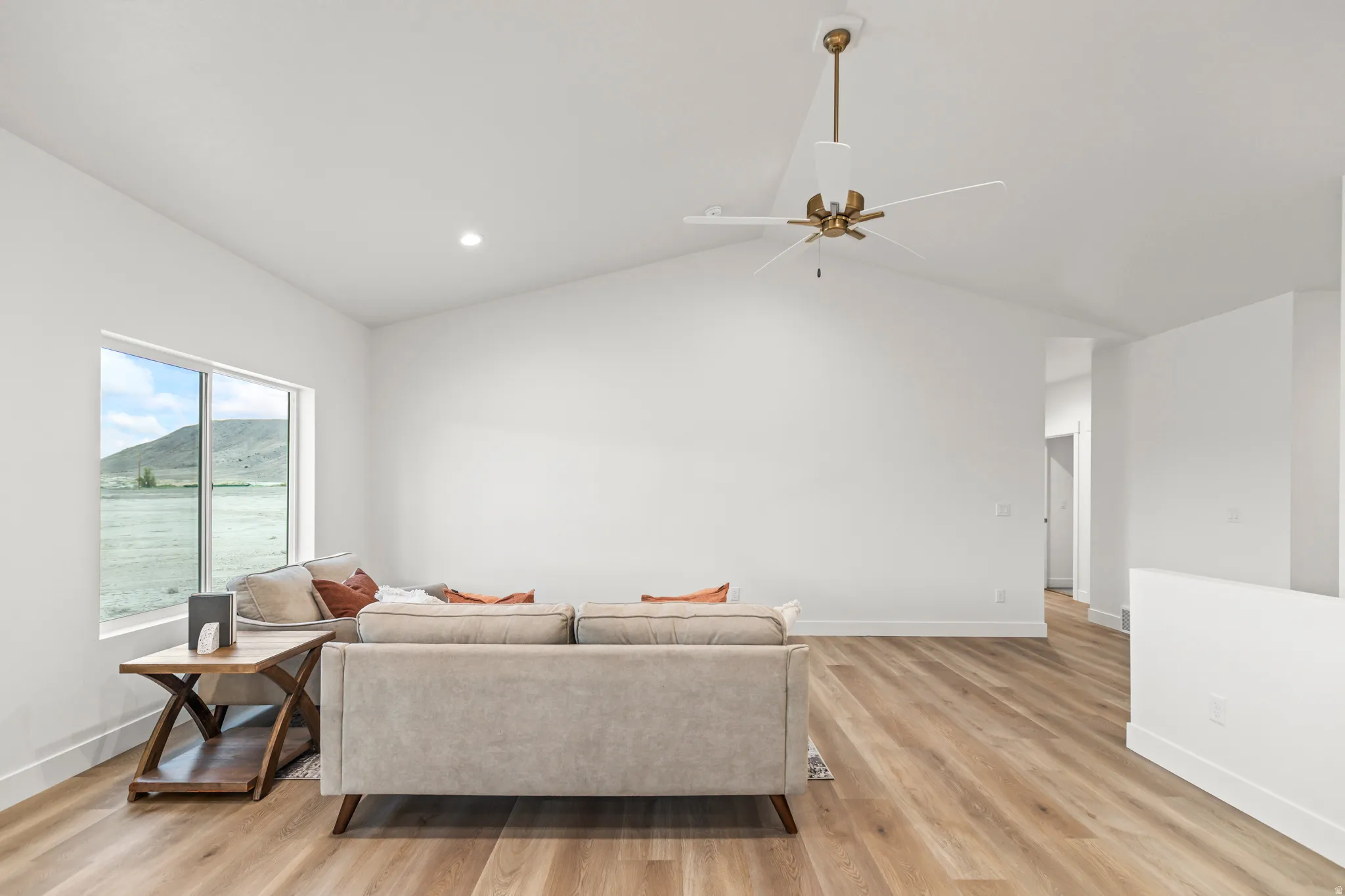 Vaulted ceiling, recessed lighting, wood-finish flooring, large window, and a ceiling fan with light