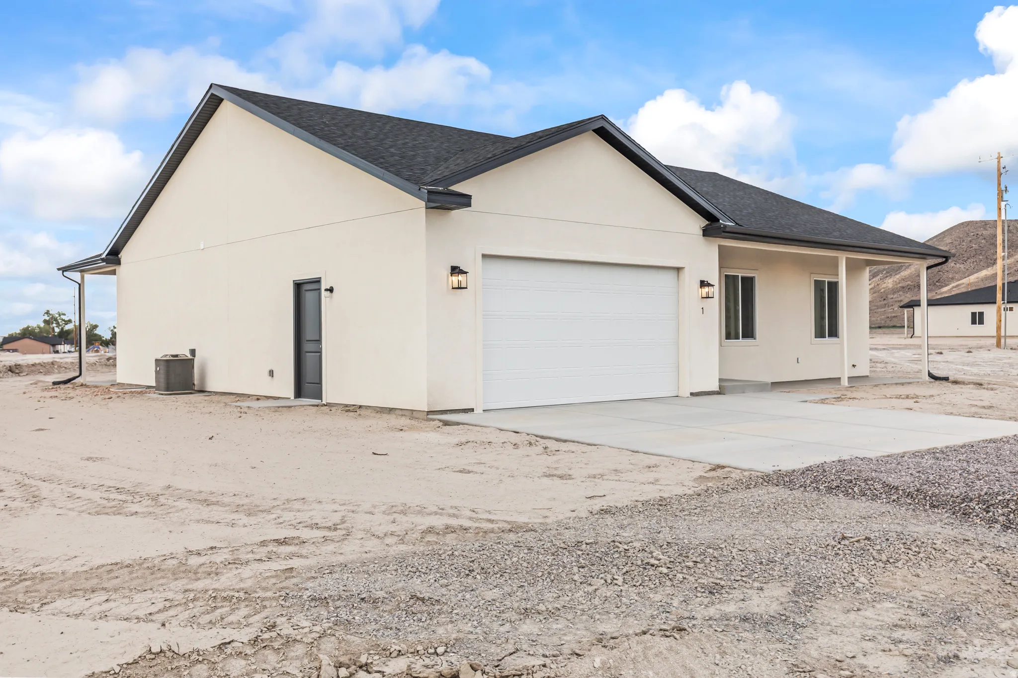 Stucco exterior with a dark shingle roof, attached garage with a white door, concrete driveway, and covered porch entry
