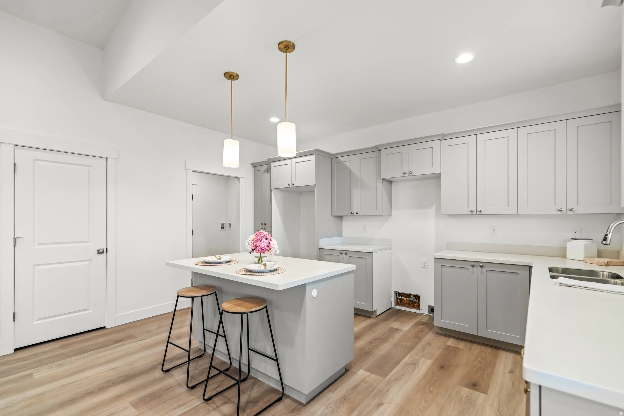 Kitchen featuring wood-finish flooring, recessed lighting, brass-finish pendant lights, light gray cabinetry, and white countertops