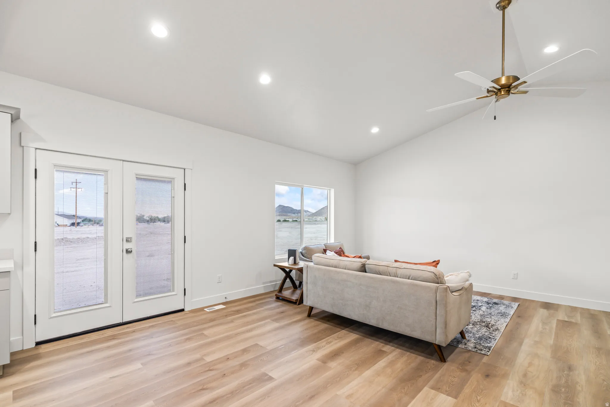 Vaulted ceiling with recessed lighting, wood-finish flooring, white double French doors, and a contemporary ceiling fan