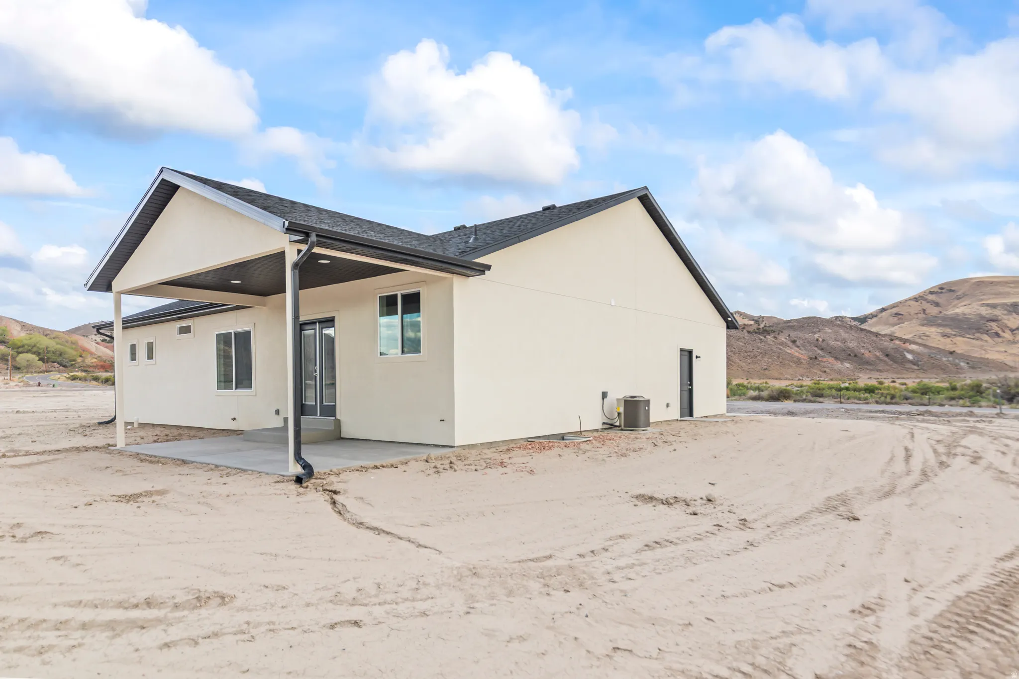 Rear exterior with a covered patio, multiple windows, and a prominent mountain backdrop