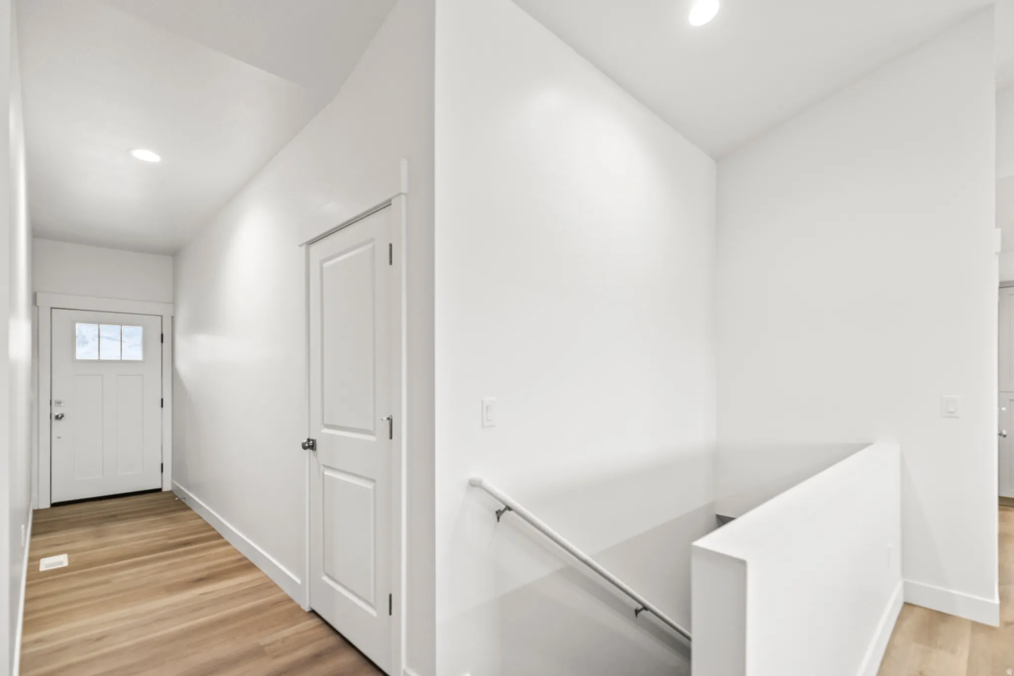 Entryway featuring wood-finish flooring, recessed lighting, and a white paneled door