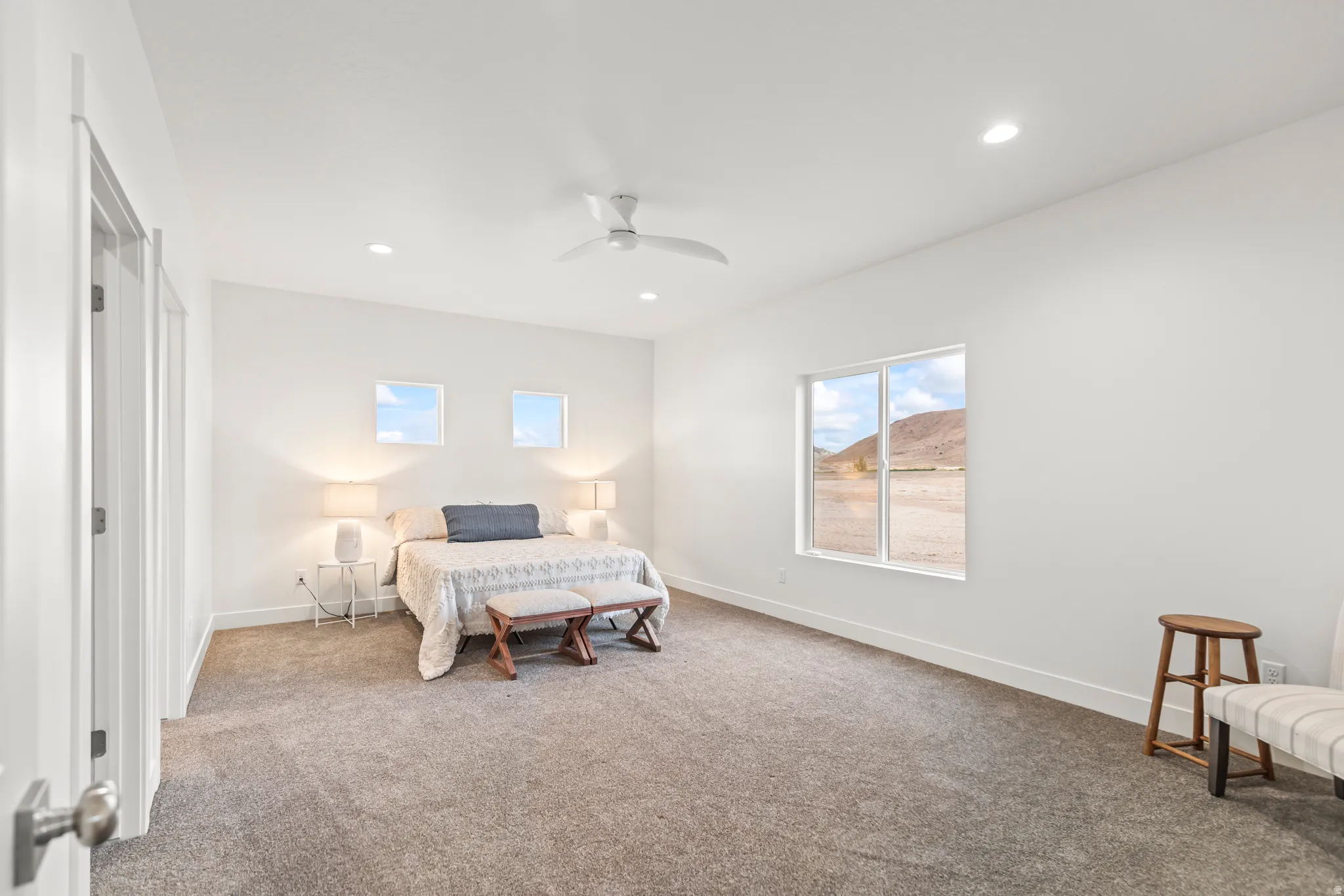 Spacious room featuring neutral carpeting, a modern ceiling fan, recessed lighting, and large windows with mountain scenery