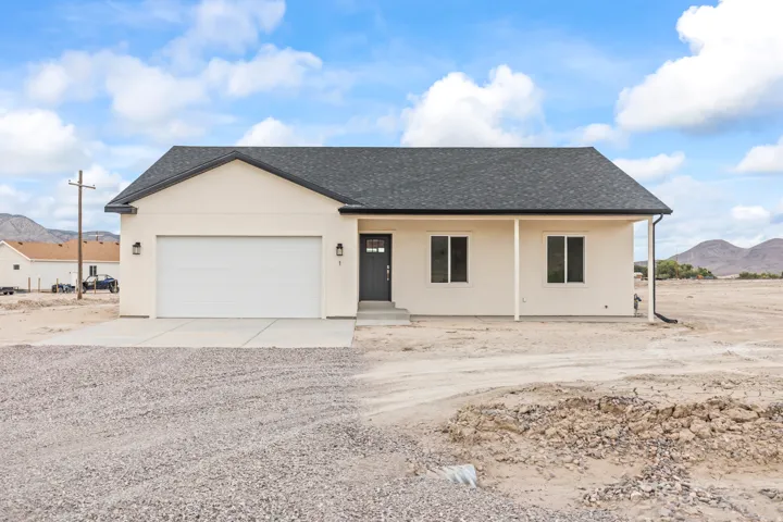 Stucco exterior with a dark shingle roof, attached garage, concrete driveway, and covered front entry