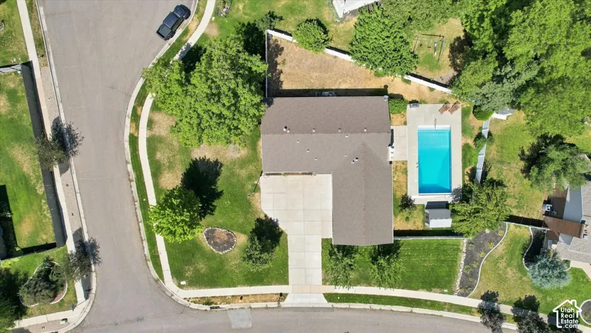 Aerial view showcasing a modern residence with a dark-toned roof, complemented by a sparkling saltwater pool.