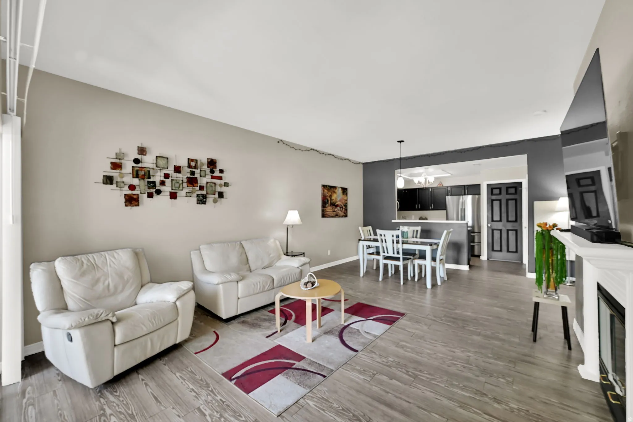 Wood-finish flooring throughout, a built-in fireplace with a white mantel, and a kitchen pass-through