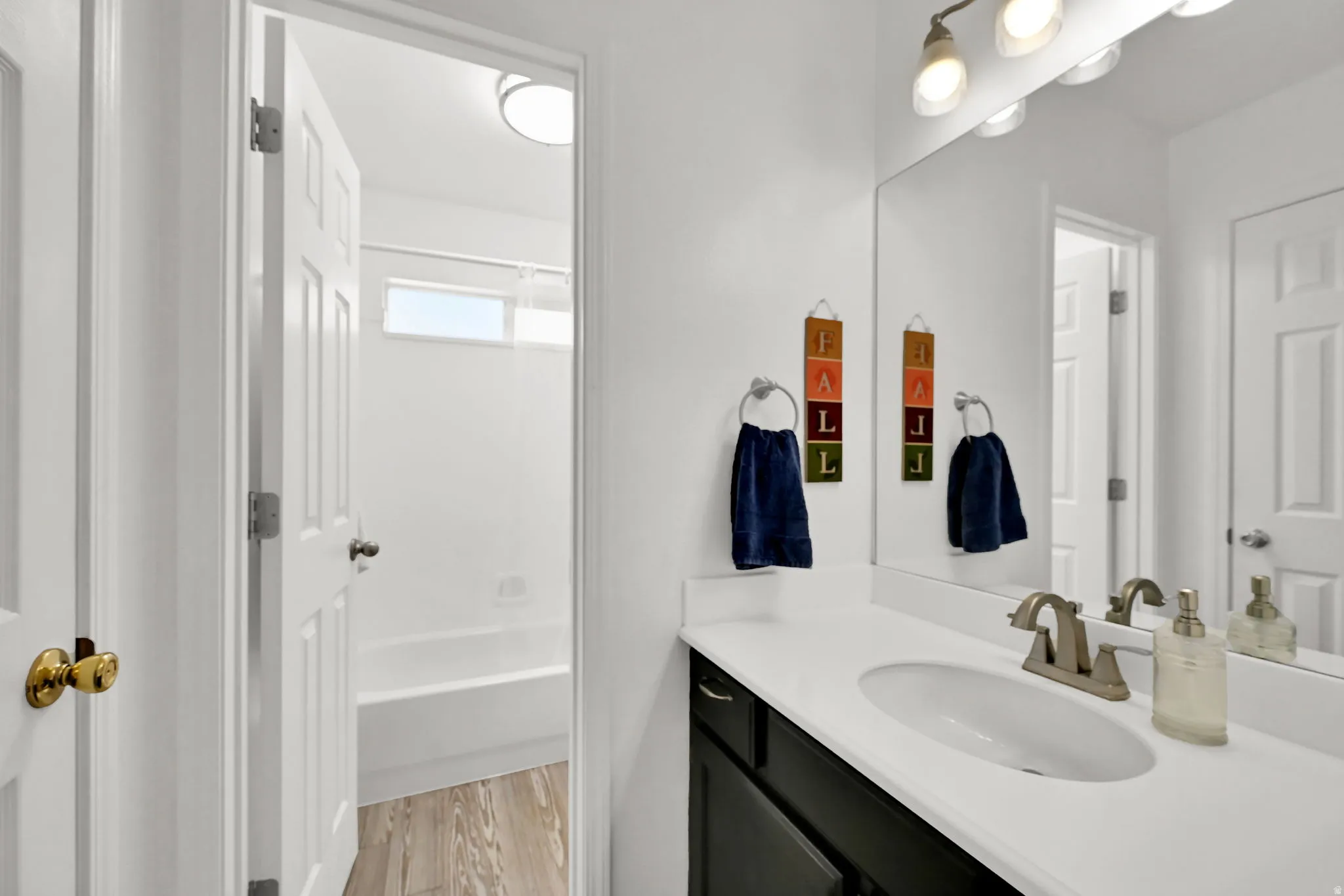 White vanity with an integrated sink, brushed nickel faucet, and a large wall-mounted mirror