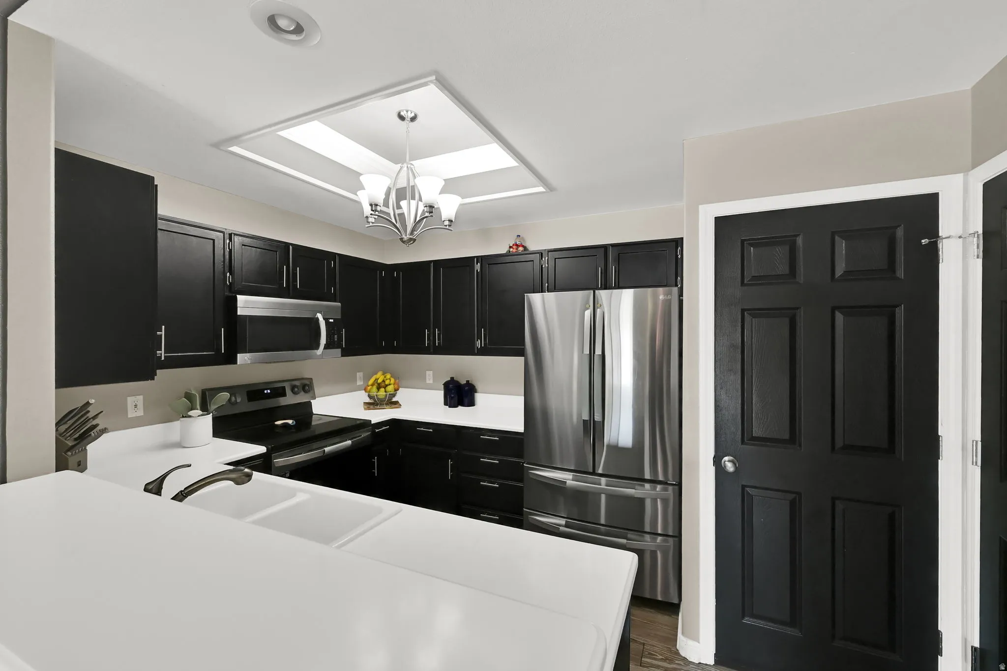 Kitchen featuring black cabinetry, white countertops, stainless steel appliances, a double basin sink, and recessed lighting