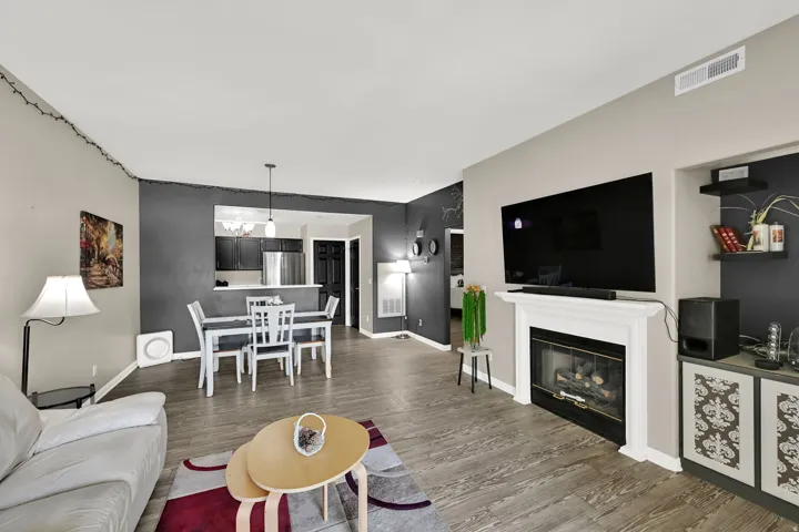 Wood-finish flooring, a white mantel fireplace, and recessed lighting create a cohesive living space