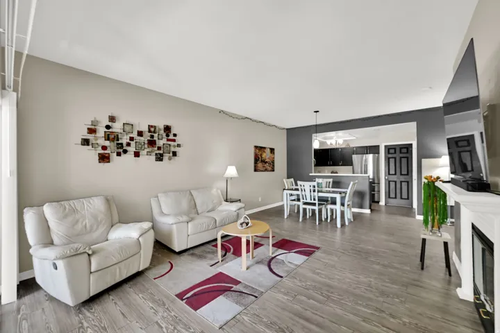 Wood-finish flooring throughout, a built-in fireplace with a white mantel, and a kitchen pass-through