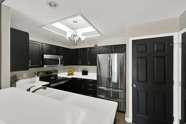 Kitchen featuring black cabinetry, white countertops, stainless steel appliances, a double basin sink, and recessed lighting
