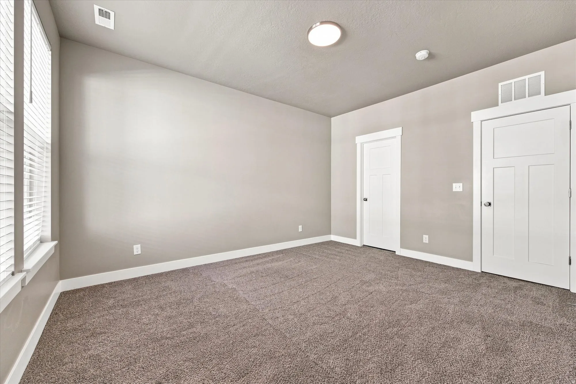 bedroom with high ceiling with recessed lighting, two panel doors, and neutral carpeting.