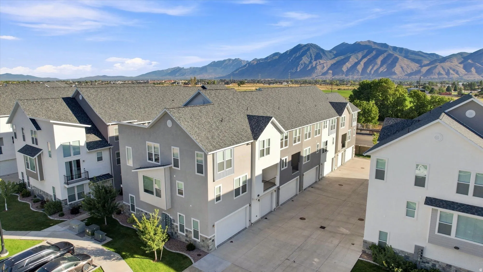 Modern multi-story buildings featuring neutral-toned siding, attached garages, and a paved drive.