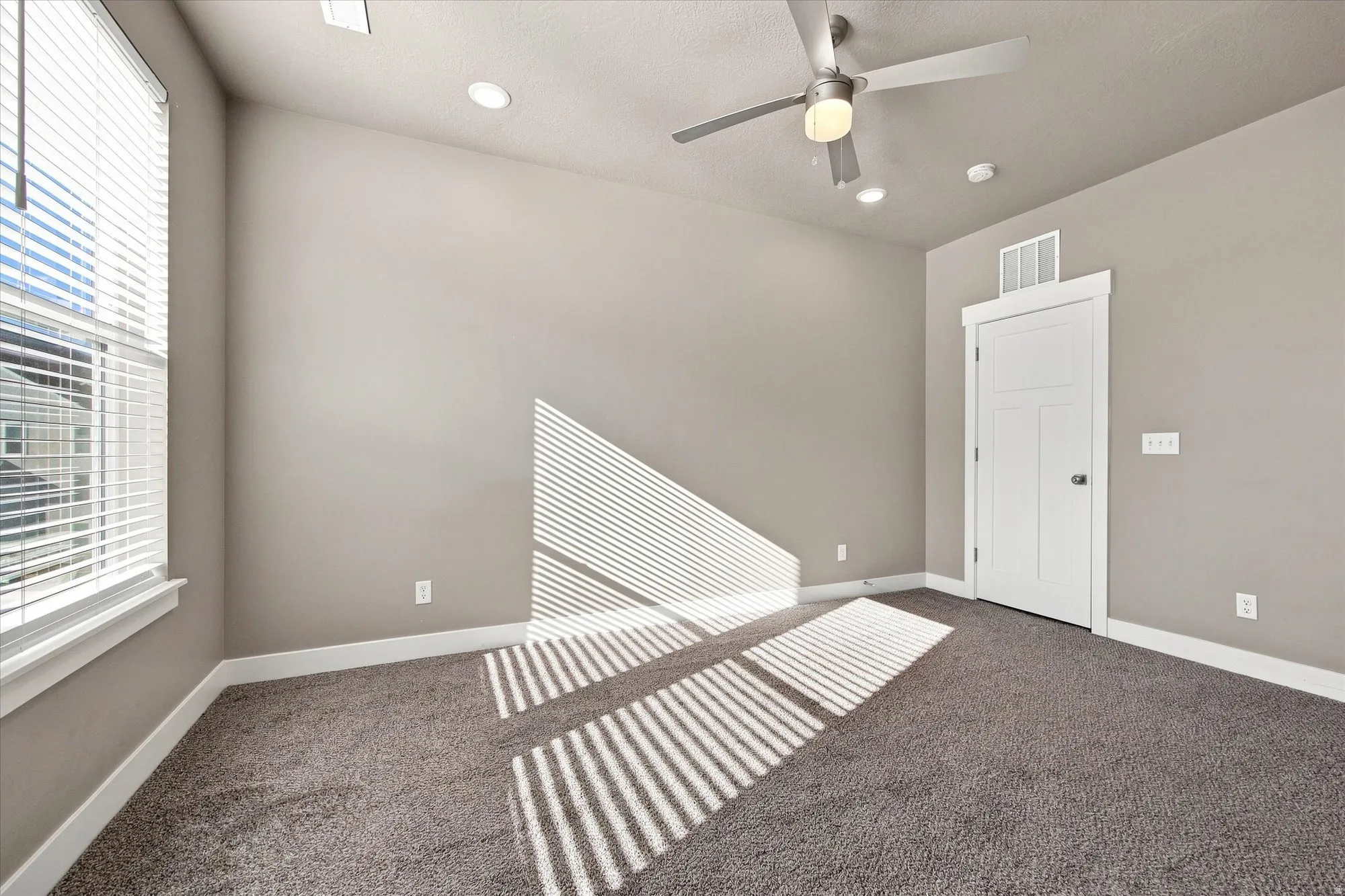 Vaulted ceiling in owners suite, with recessed lighting and a ceiling fan, window with blinds that gives a lot of natural light, panel door, and carpeted flooring