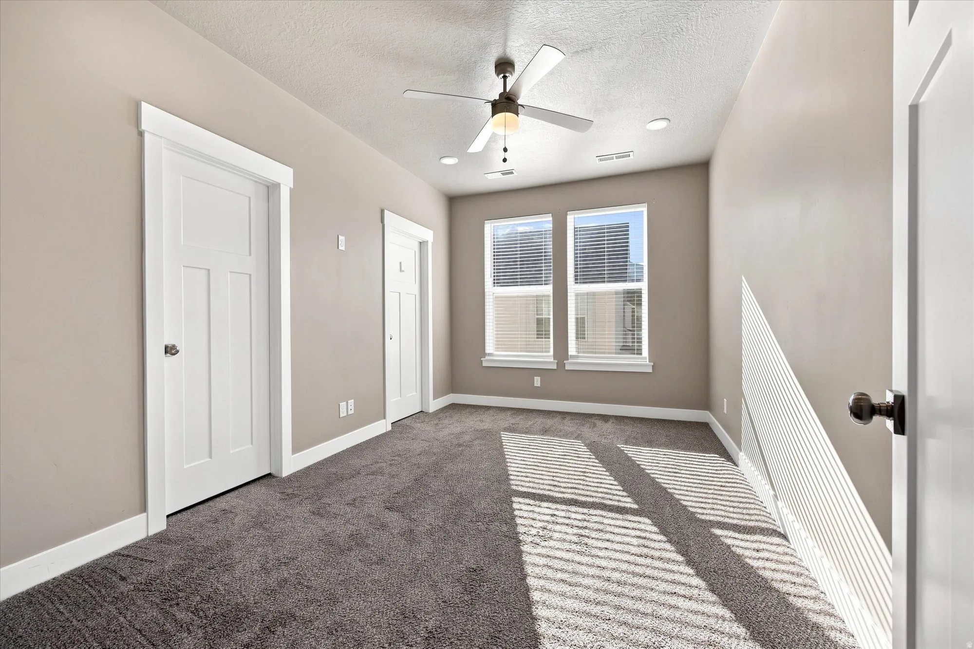 Owners suite carpeted bedroom featuring a walk in closet, ceiling fan, recessed lighting, connecting bathroom, and dual pane windows.