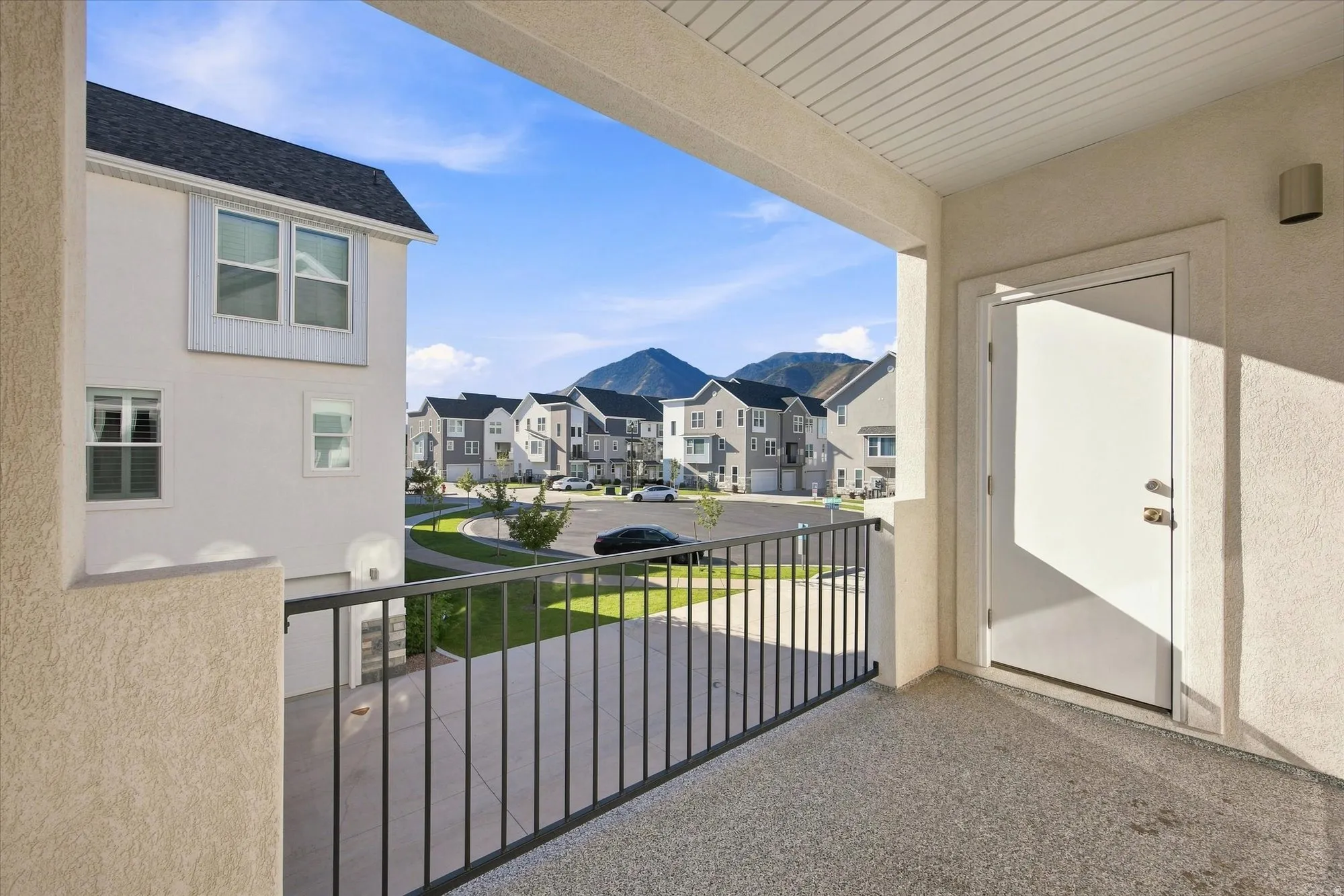 Balcony with durable aggregate flooring, white exterior door, and black metal railing. Balcony off of kitchen in the back.