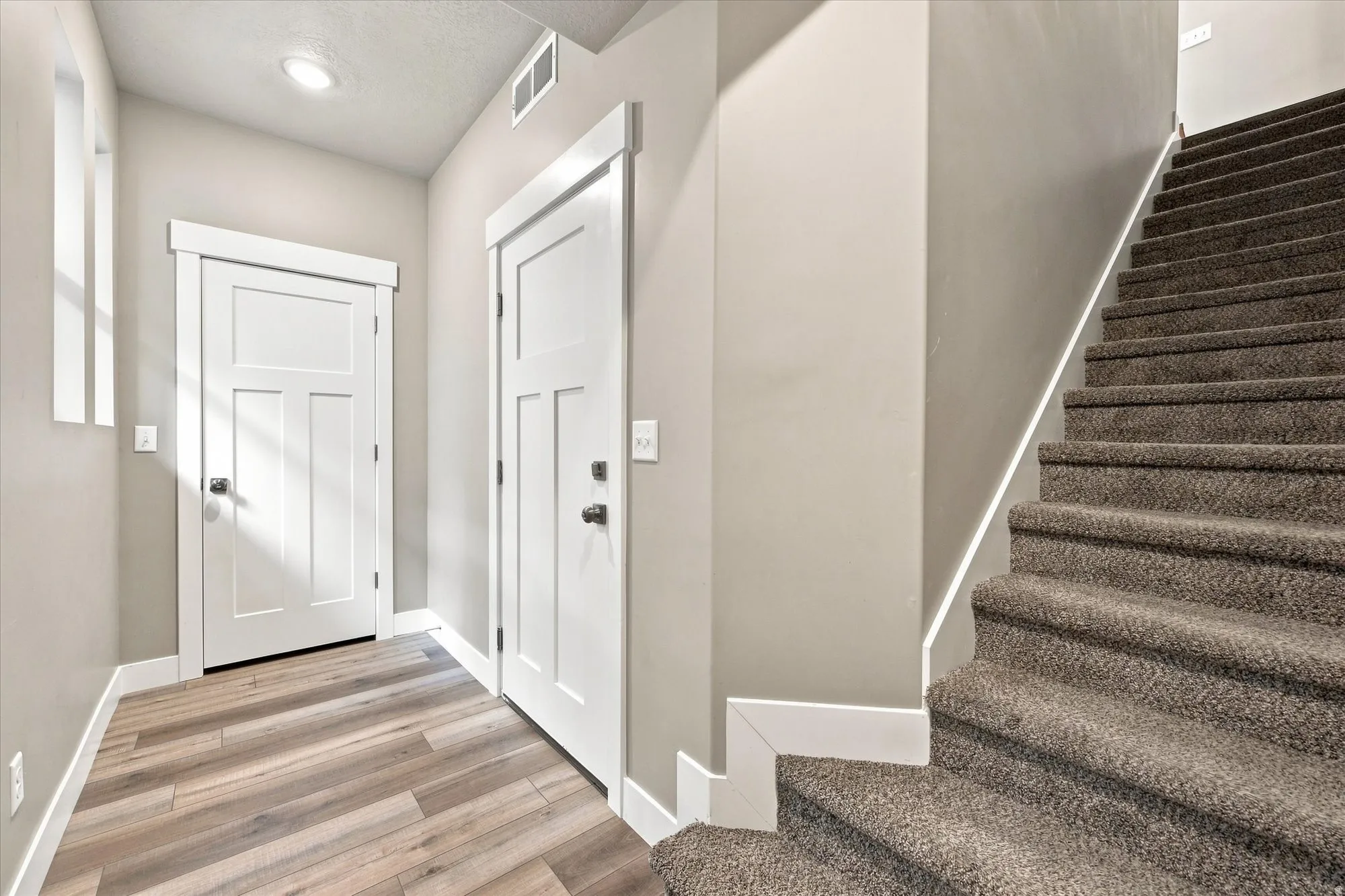 Wood-finish flooring, recessed lighting, white panel doors with storage closet and garage entrance.