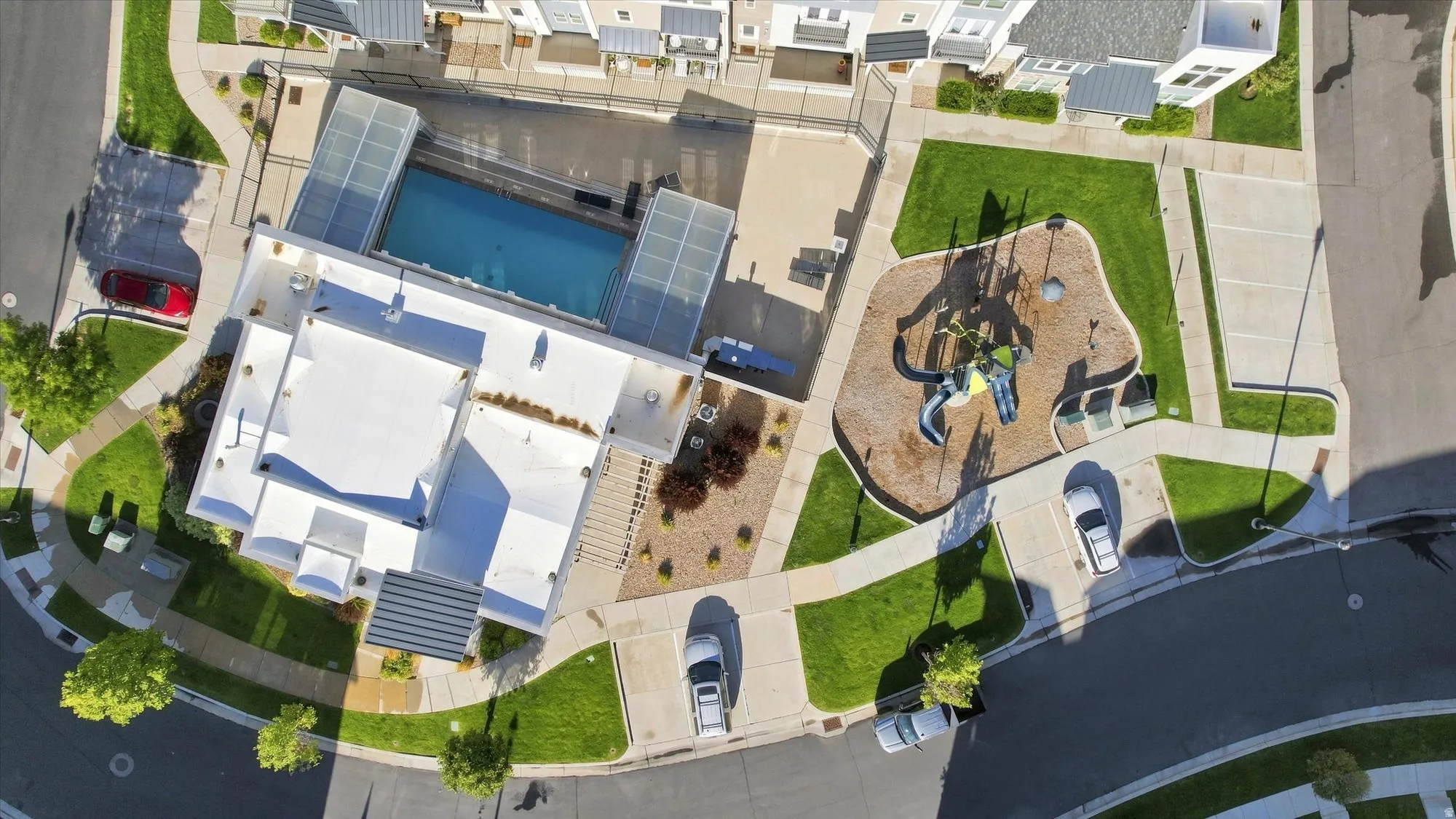Community amenities featuring a swimming pool with partial enclosure, a dedicated playground area, surrounding green spaces, and paved pedestrian pathways