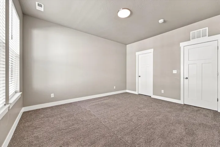 bedroom with high ceiling with recessed lighting, two panel doors, and neutral carpeting.