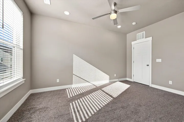 Vaulted ceiling in owners suite, with recessed lighting and a ceiling fan, window with blinds that gives a lot of natural light, panel door, and carpeted flooring