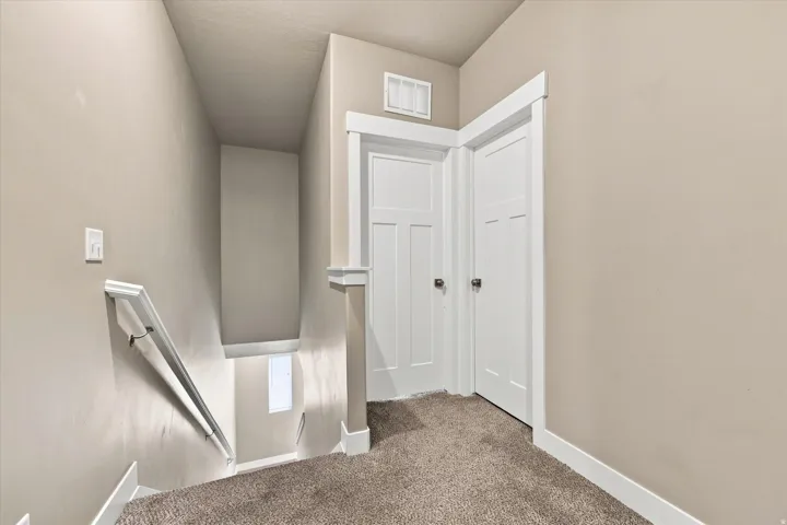 Neutral-toned walls with contrasting white trim, carpeted flooring, and a white handrail. Second floor landing.