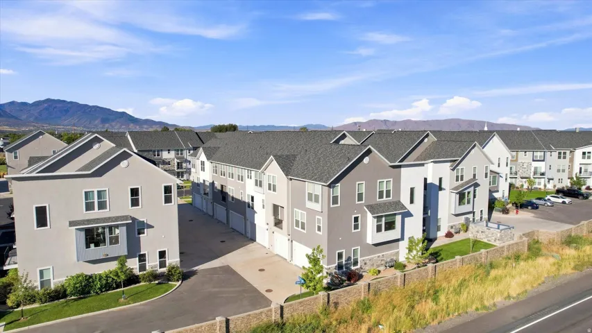 Modern townhome community featuring multi-story units, attached garages, and a paved parking area.