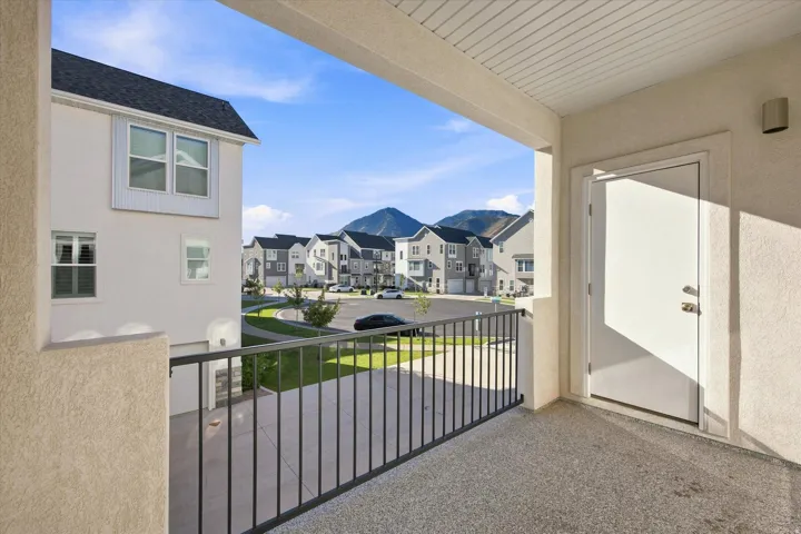 Balcony with durable aggregate flooring, white exterior door, and black metal railing. Balcony off of kitchen in the back.