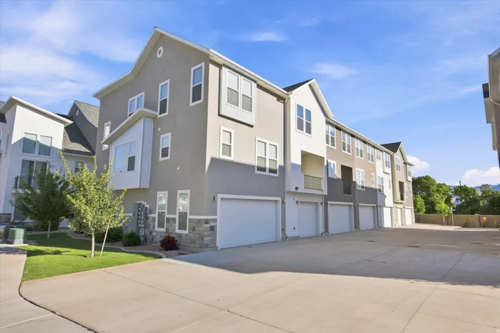 Multi-level exterior with stucco and stone accents, individual garage doors, and a prominent bay window.