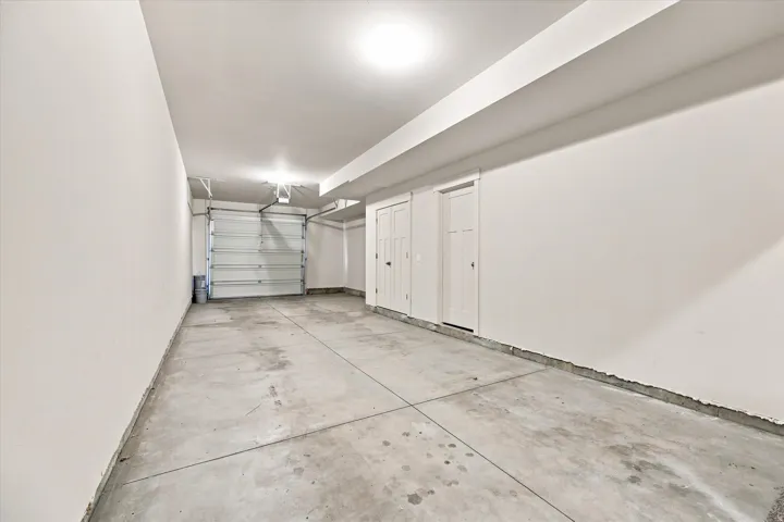 Attached garage with a concrete floor, overhead lighting, and two interior doors.