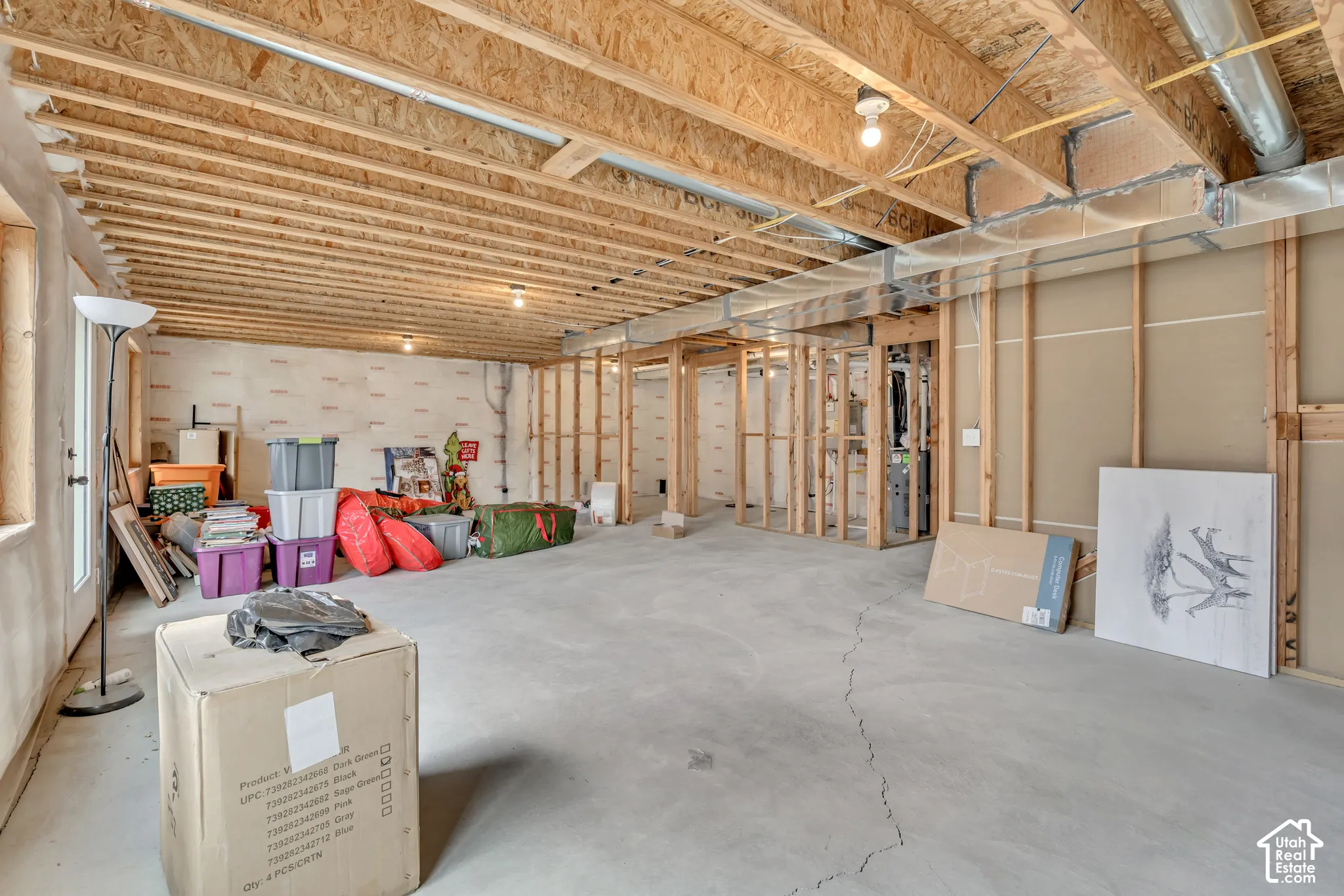 Unfinished basement featuring exposed wood joists, concrete flooring, and framed interior walls