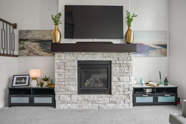 Stone-clad fireplace with dark wood mantel and a gas insert